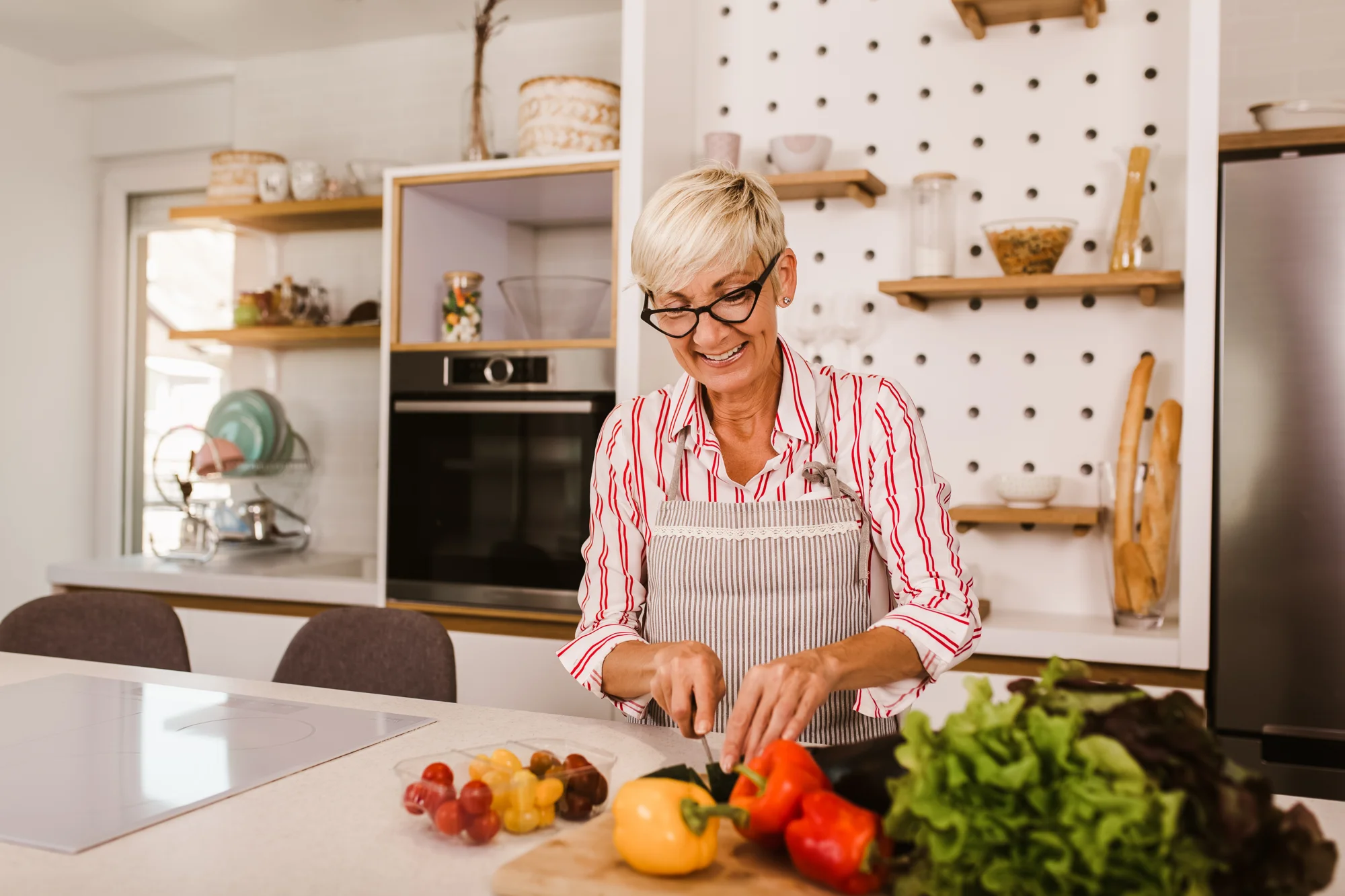 Senhora preparando uma refeição com calma em cozinha iluminada por luz natural